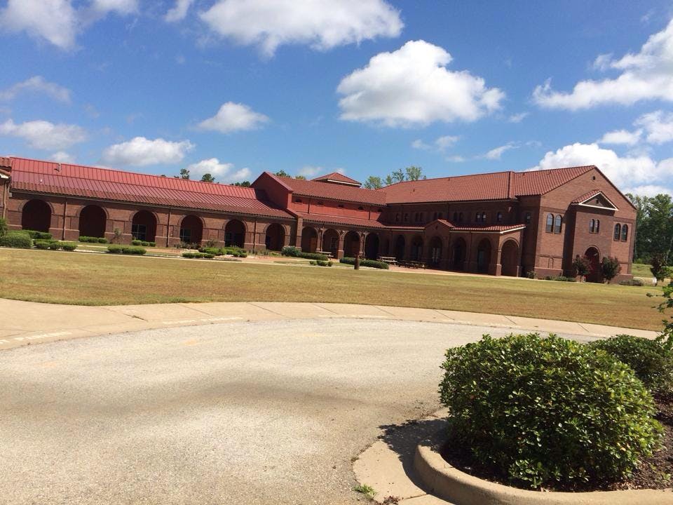 Large brick building with a red roof and arched walkways