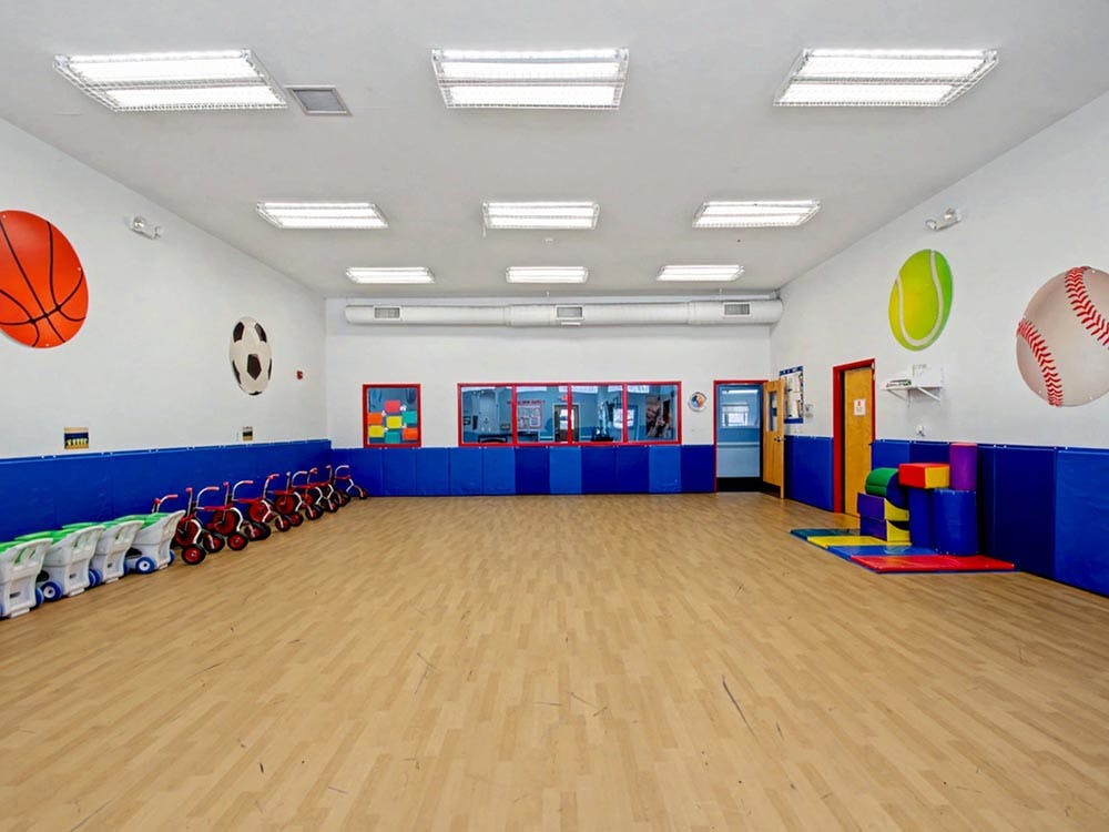 Empty playroom with sports ball decorations, small bikes, and colorful soft play equipment