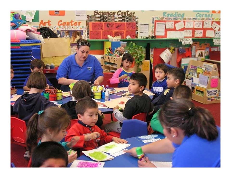 Adults and children seated at tables in a classroom