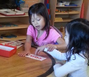 Two children looking at a word card on a table