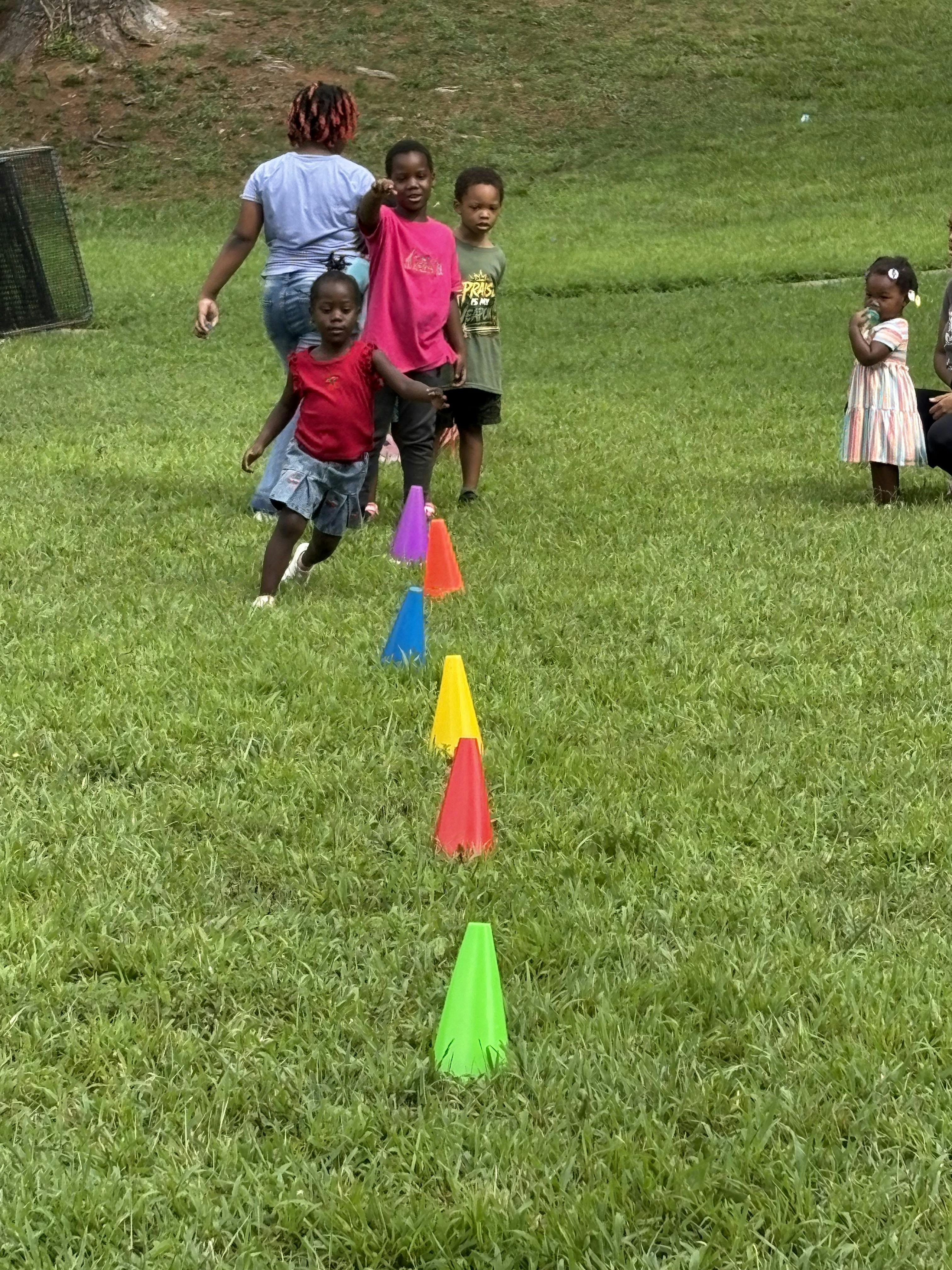 Children running among colorful cones on a grassy field