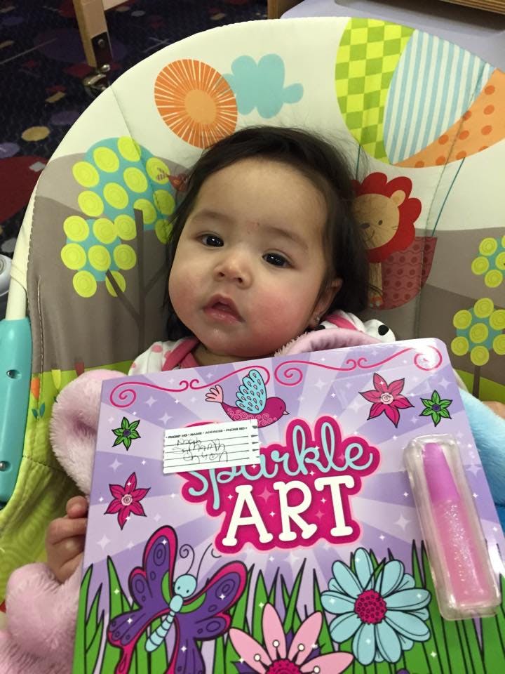 Child in a high chair holding a Sparkle Art book