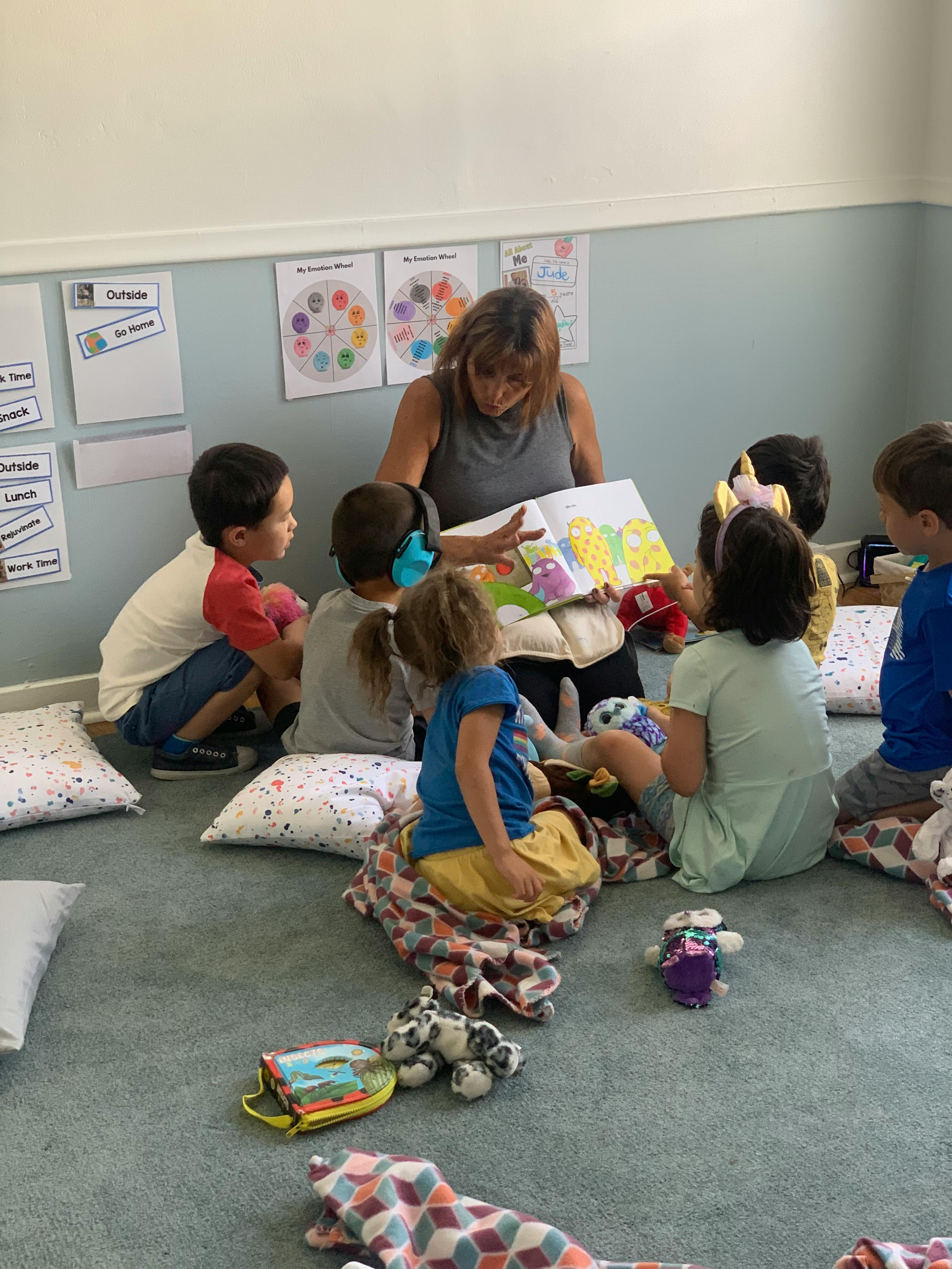 Person reading a book to a group of children in a classroom