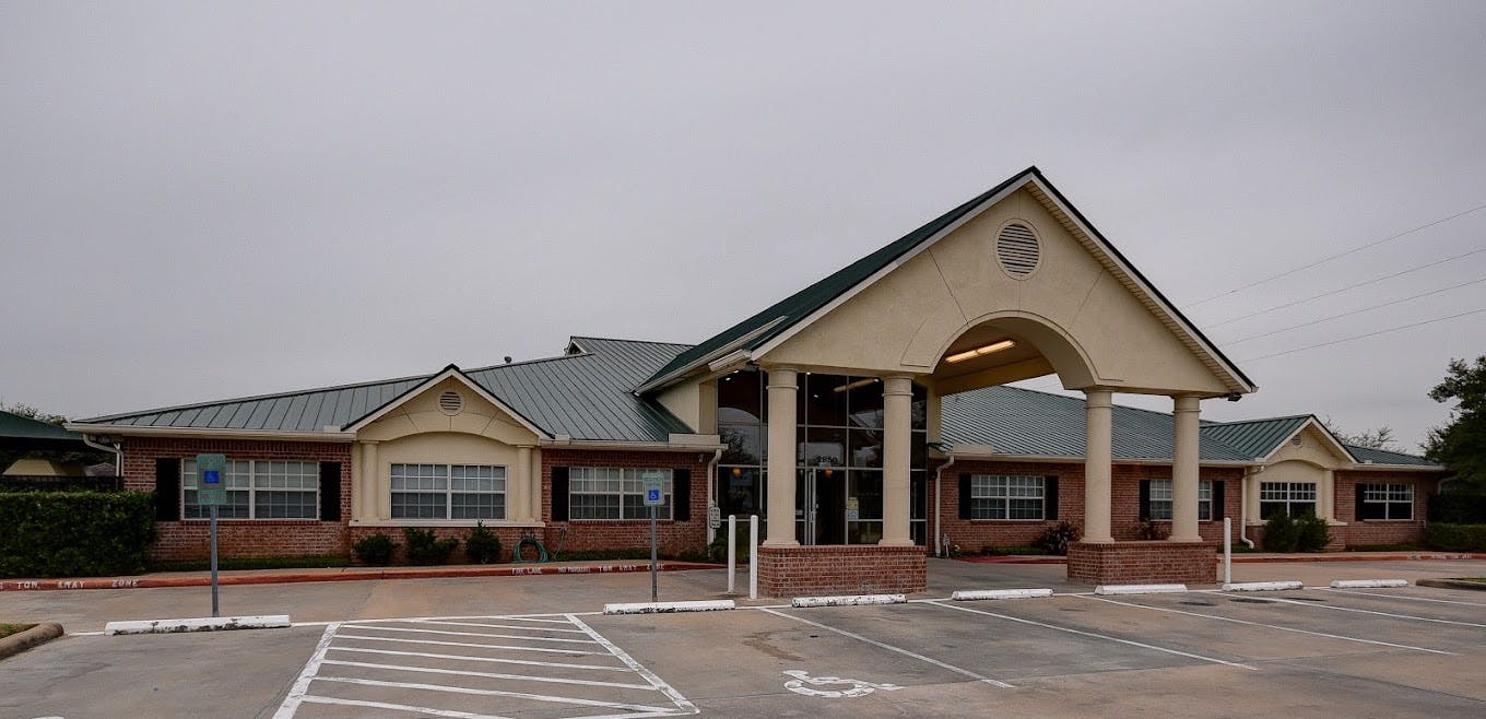 Building with a large arched entrance and a parking lot in front