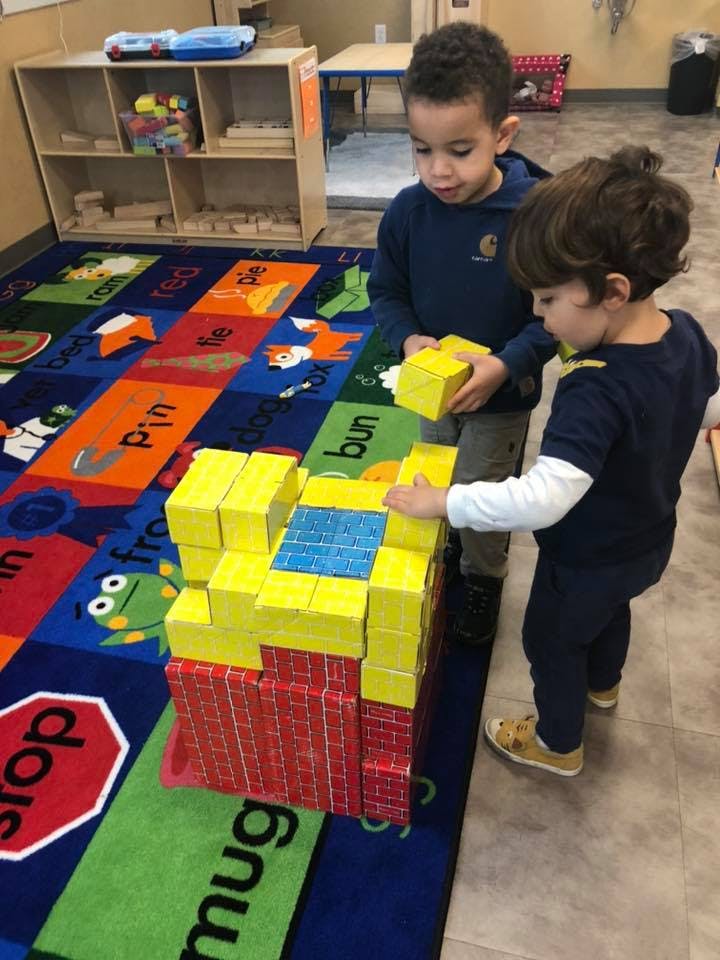 Two children building with blocks on a colorful rug