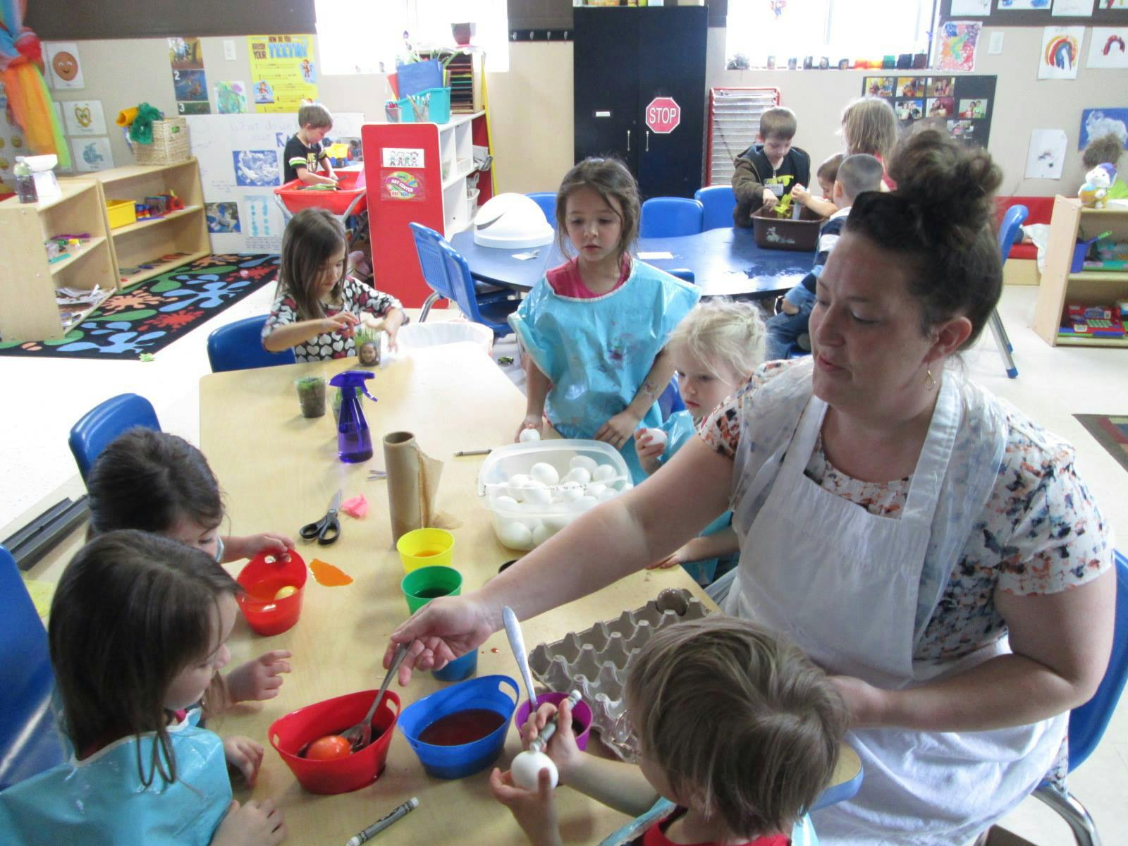 Adult and children at a table doing an art activity in a classroom