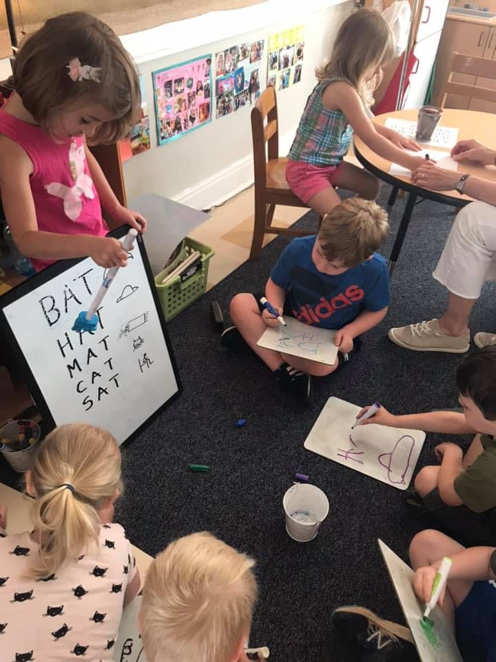 Children drawing and writing on whiteboards and paper