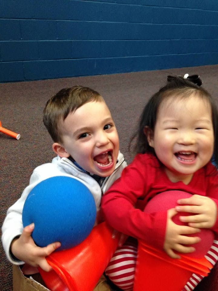 Two children holding balls and orange cones