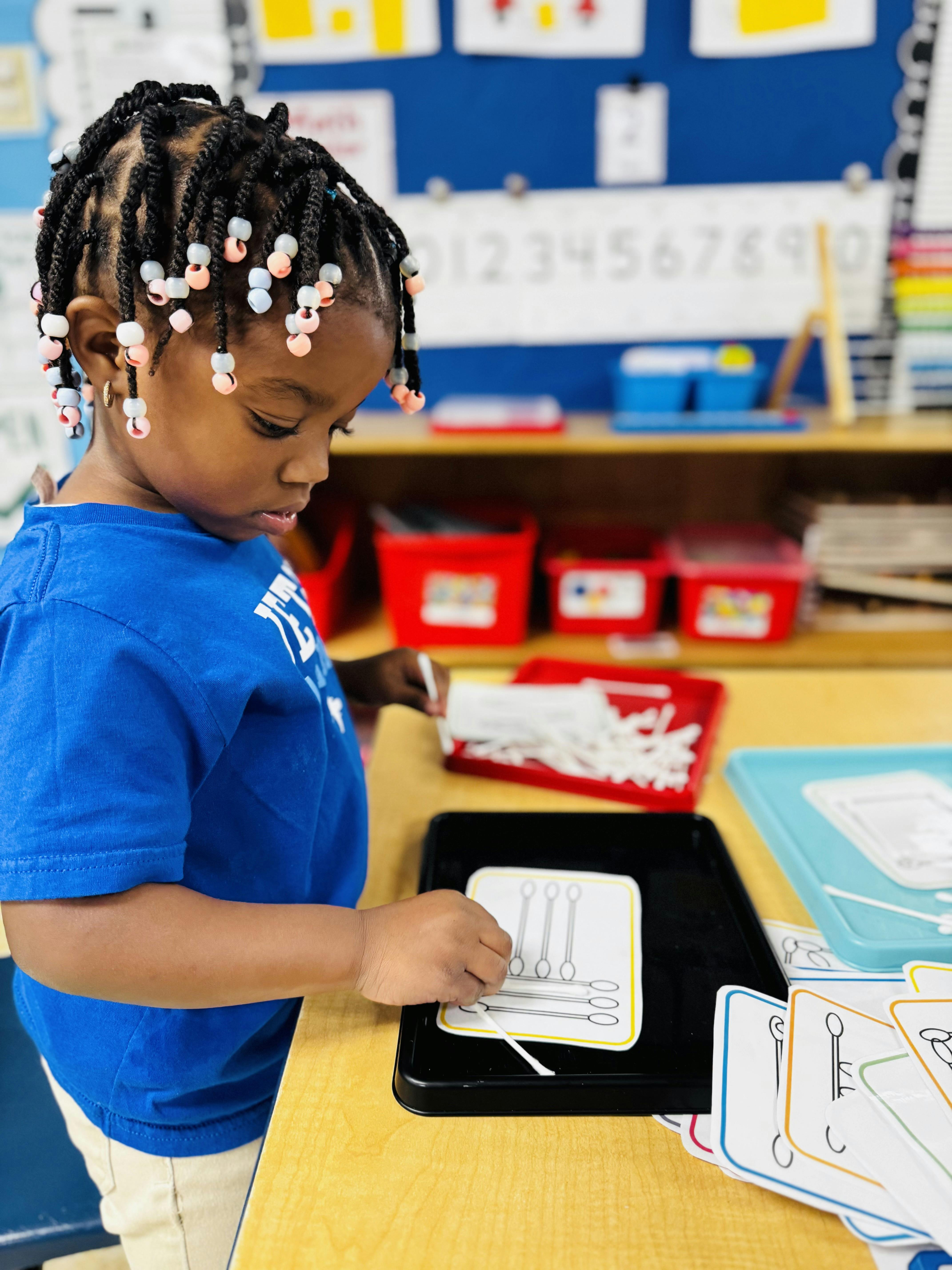 Child placing cotton swabs on a learning card in a classroom