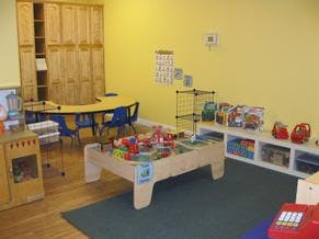 Playroom with a play table, chairs, and shelves with toys