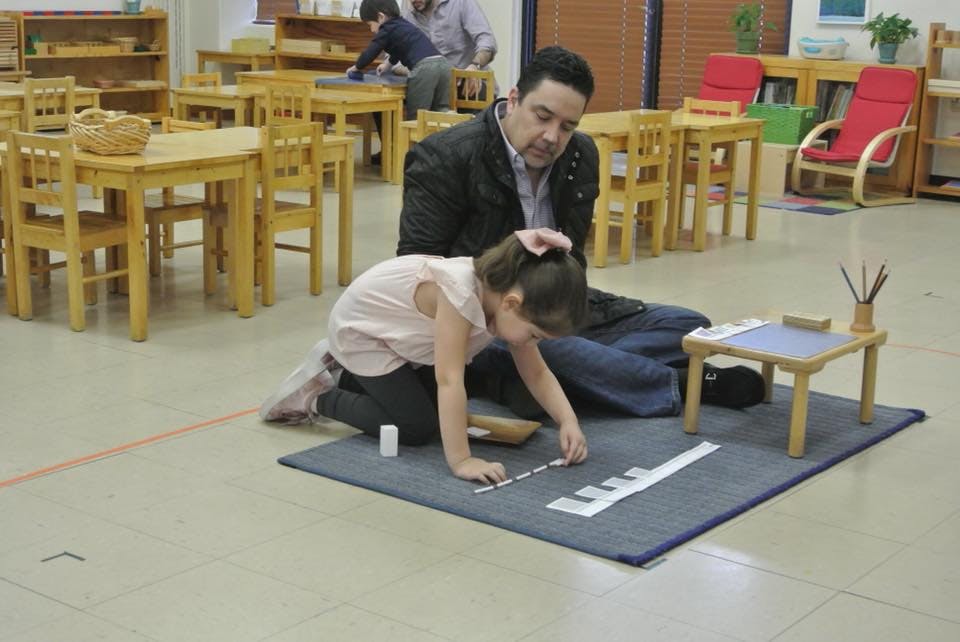 Adult and child on floor working with learning materials