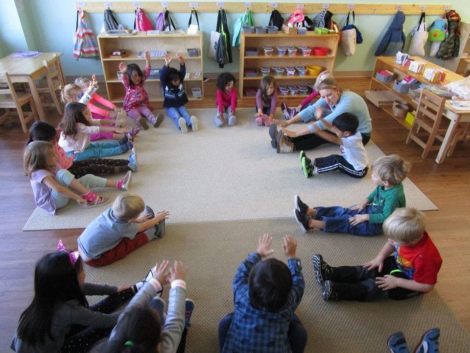 Adult and children sitting in a circle on the floor stretching