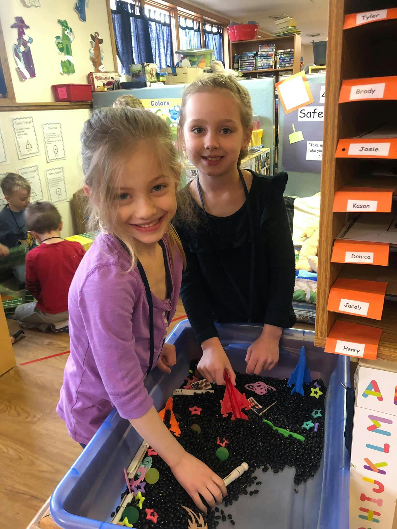 Two children playing with a sensory bin in a classroom