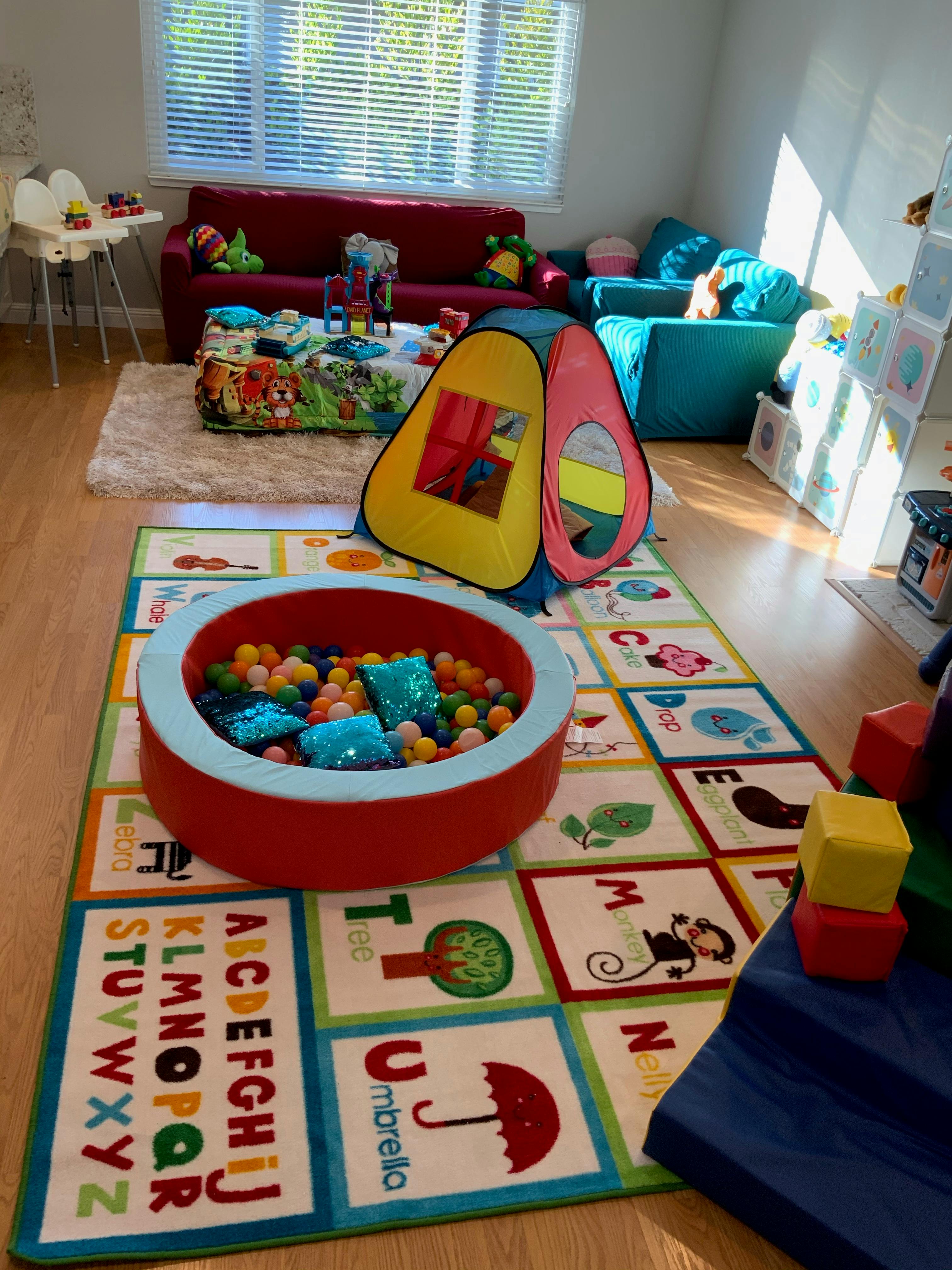 Playroom with a ball pit, play tent, and alphabet rug