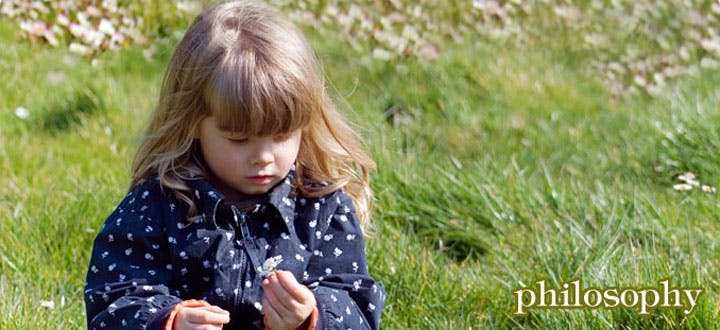 Child looking down at hands in grass
