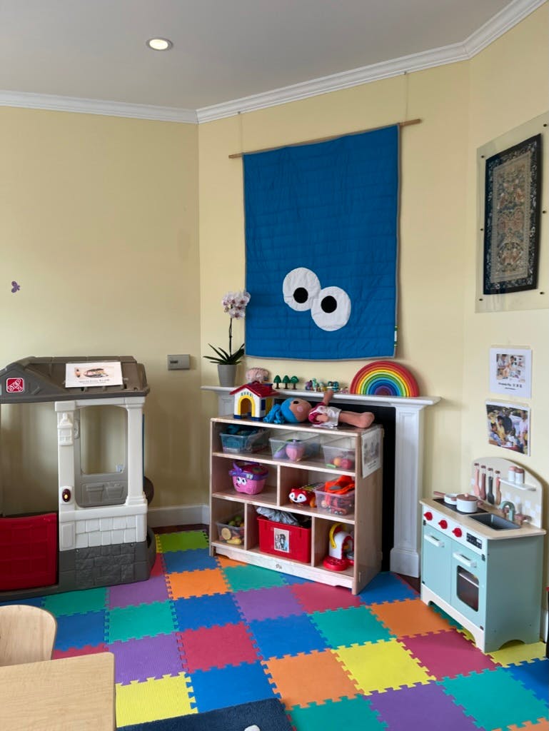 Playroom with colorful floor mats, toy kitchen, and storage shelves