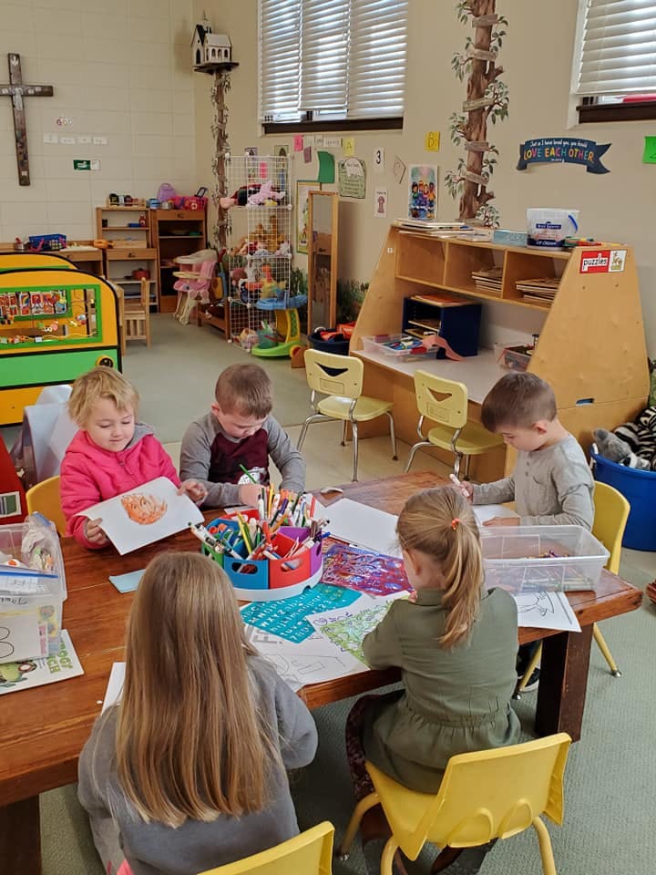 Children drawing and coloring at a table in a classroom