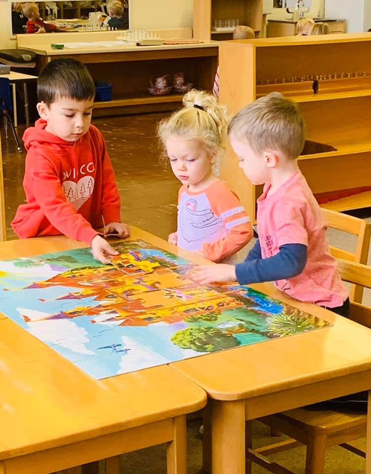 Three children working on a puzzle at a table
