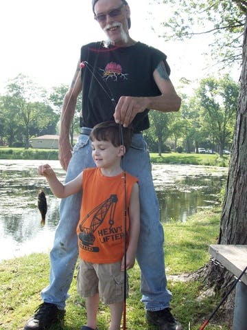 Person and child fishing by a pond, child holding a small fish