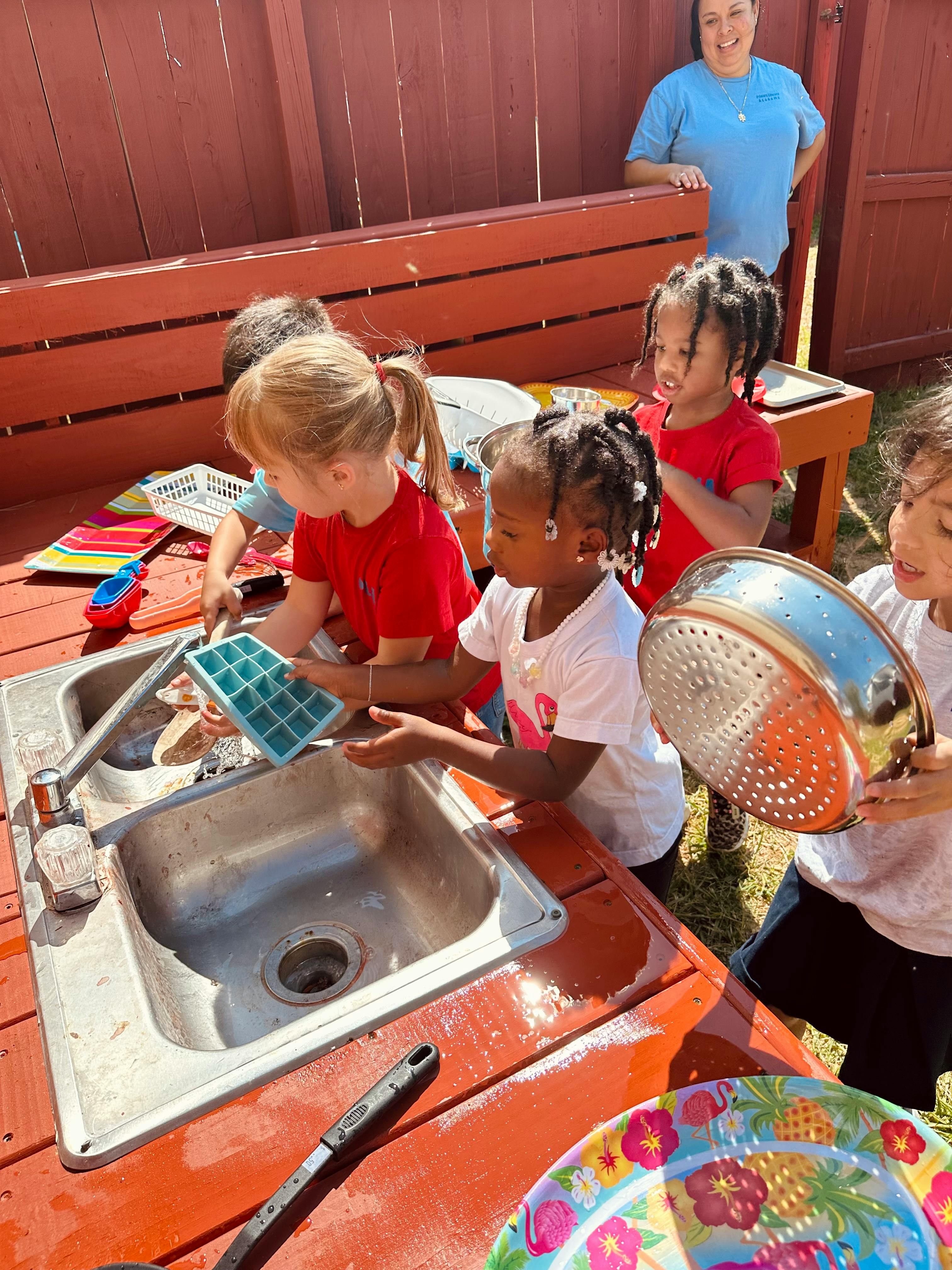 Children playing with a sink and kitchen items outdoors
