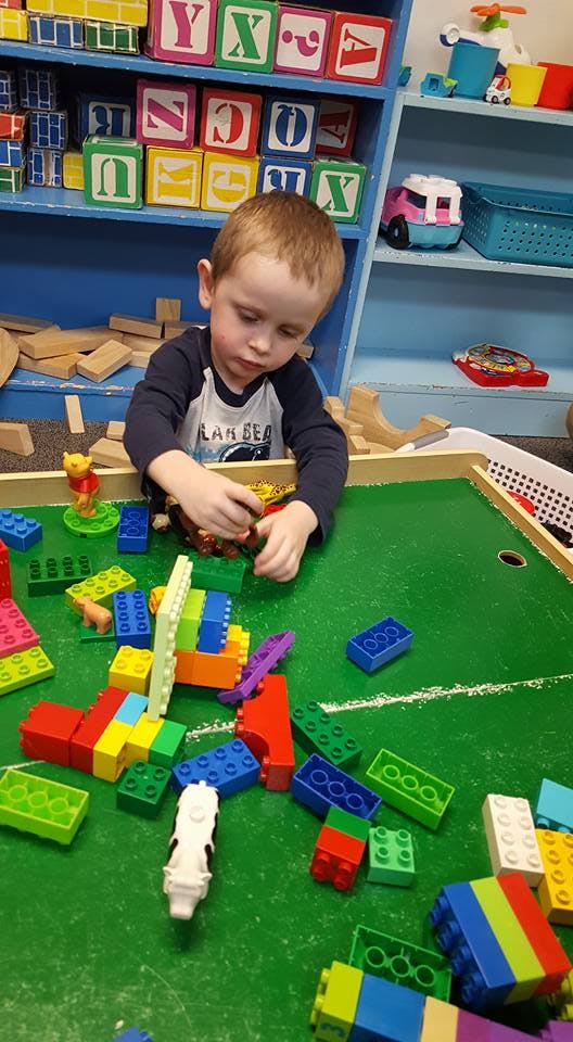 Child playing with colorful building blocks on a green table