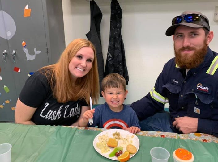 Two adults and a child sitting at a table with a plate of food