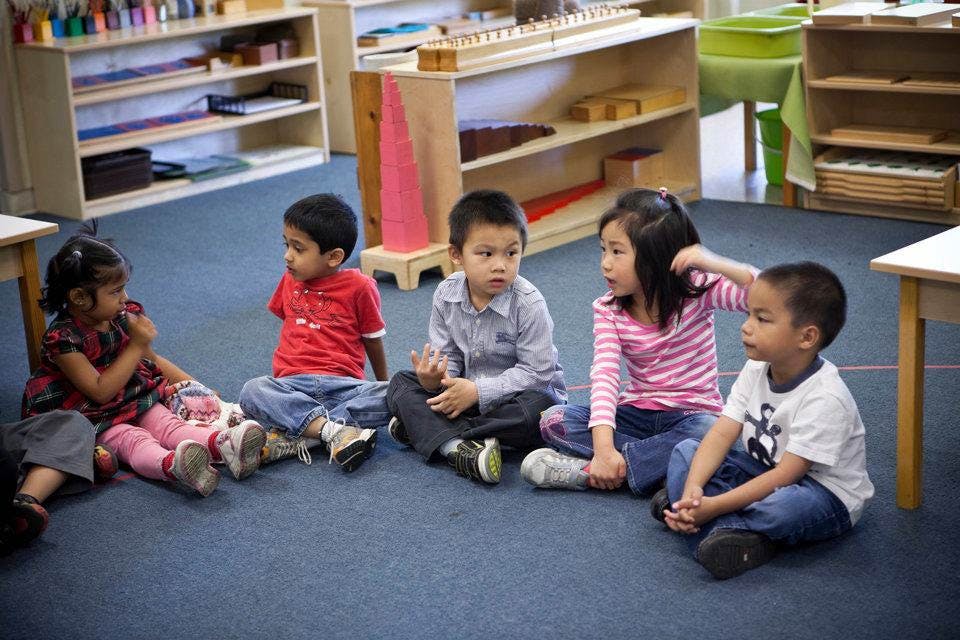Five children sitting on the floor in a classroom