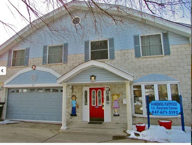 Front exterior of a two-story building with a red door and a blue sign