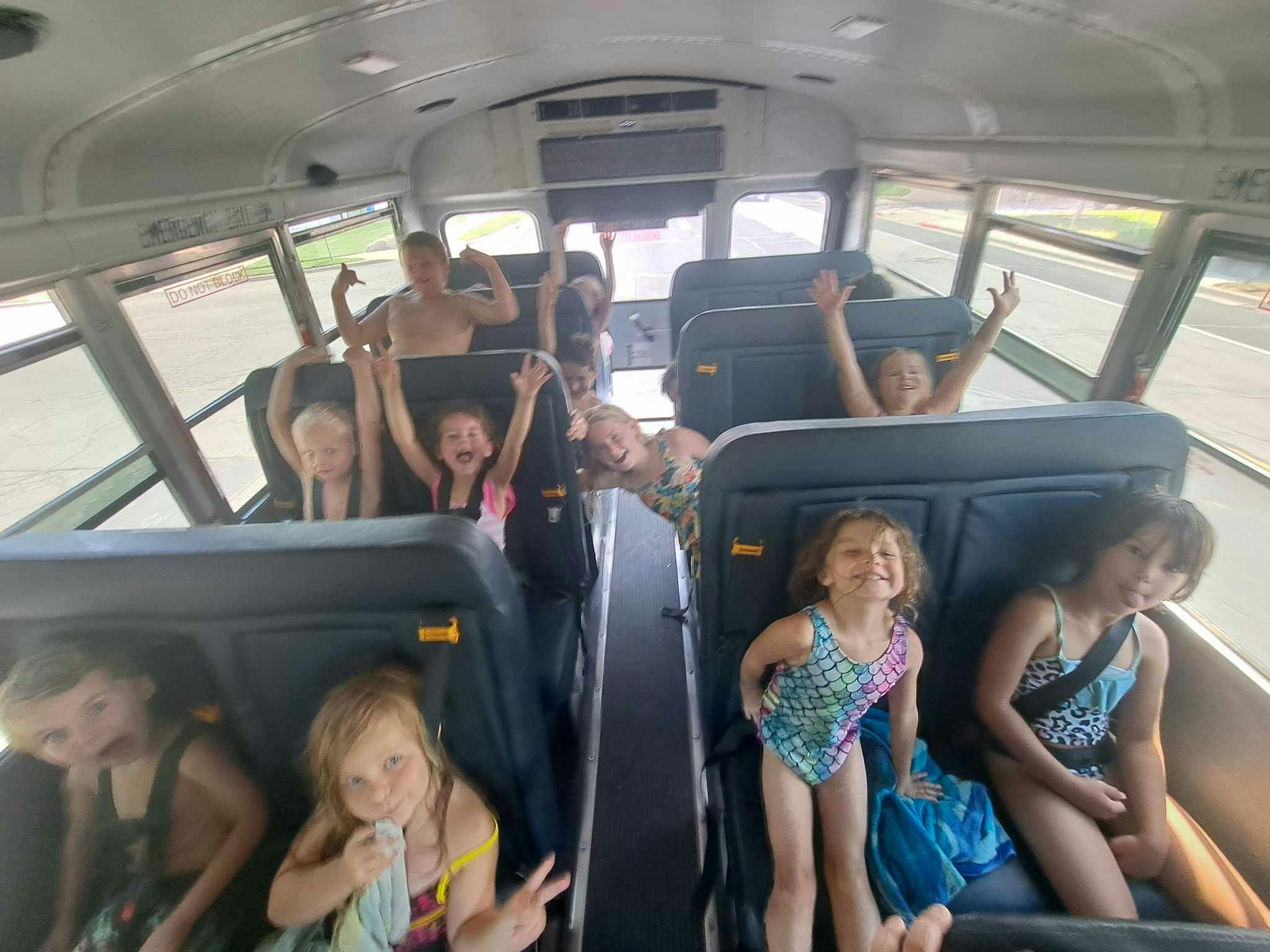 Children in swimsuits riding on a bus
