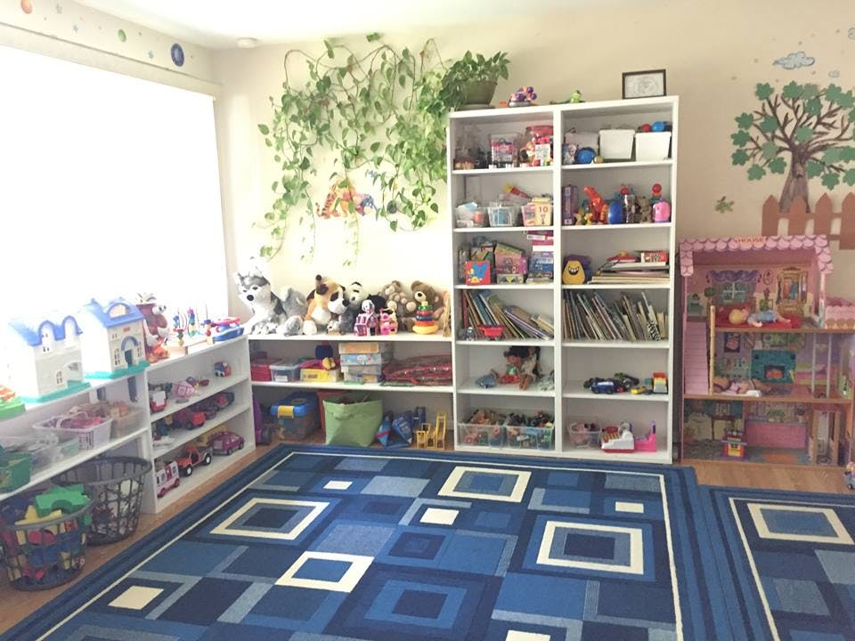 Playroom with shelves full of toys and books, blue geometric rug