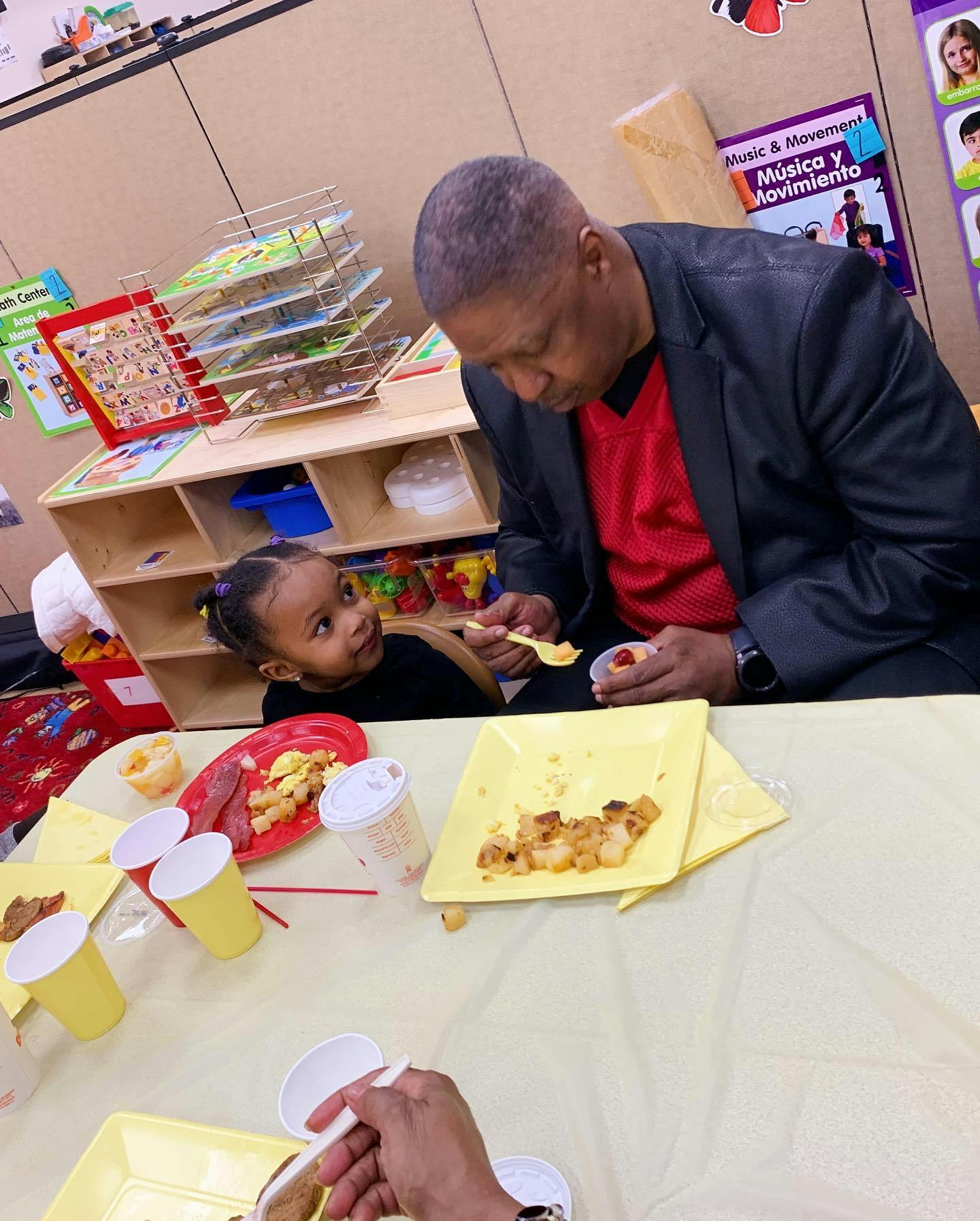 Adult and child eating at a table in a classroom