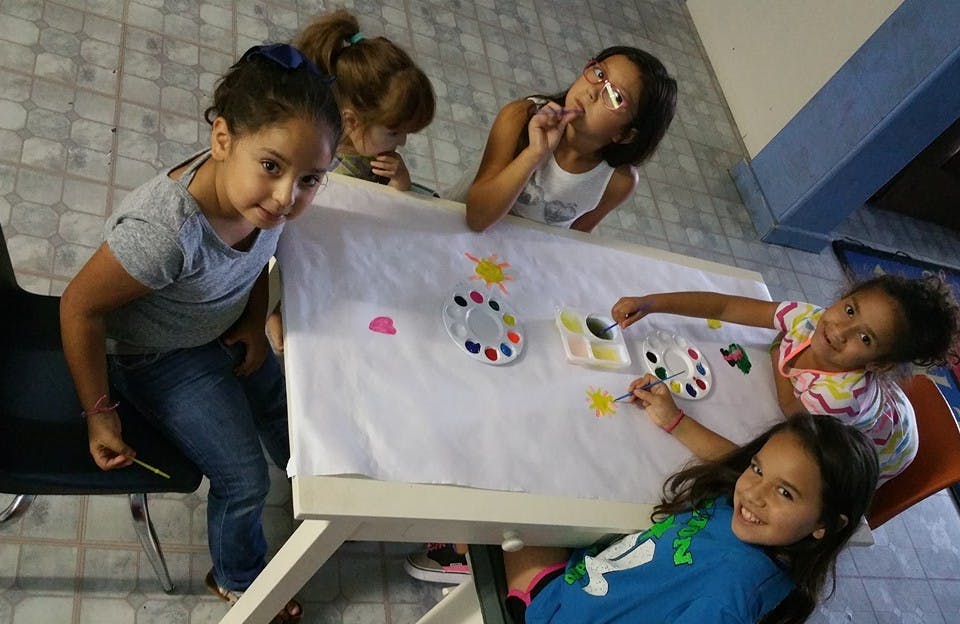 Four children painting at a table