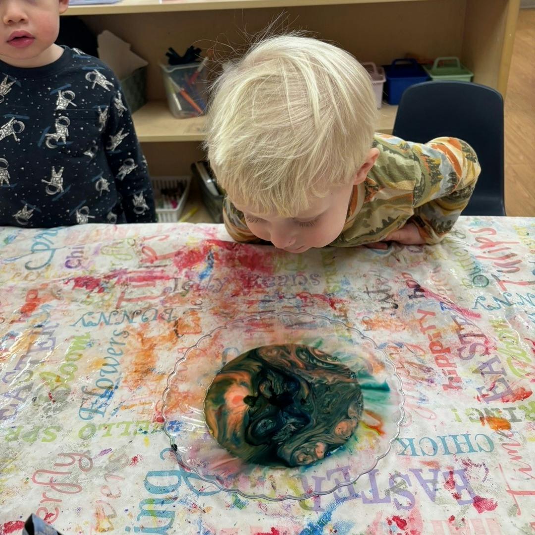 Child looking at a marbled object on a colorful table