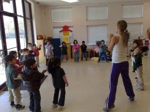 Adult leading children in an activity in a classroom