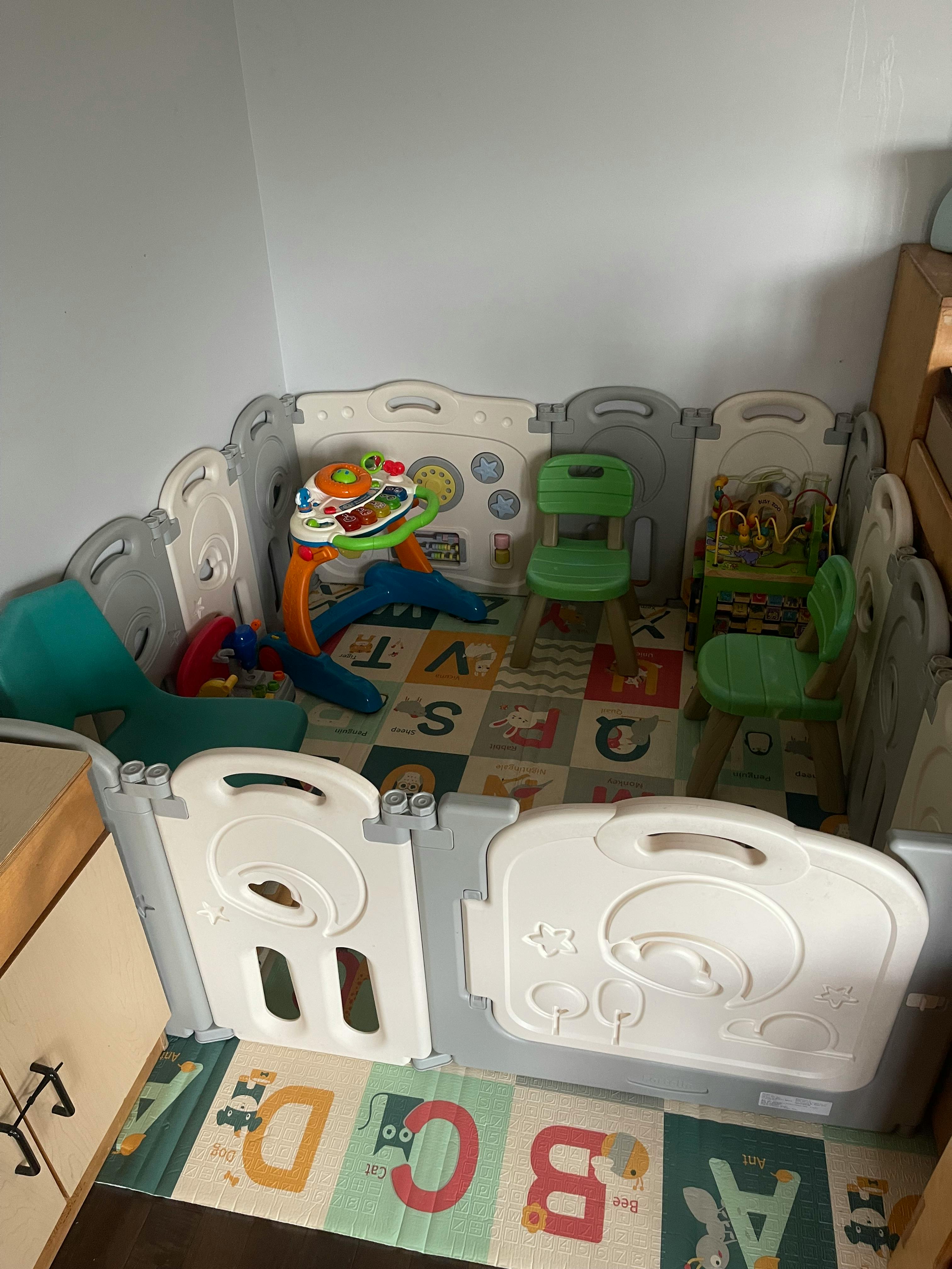 Playpen with toys and small chairs on an alphabet mat