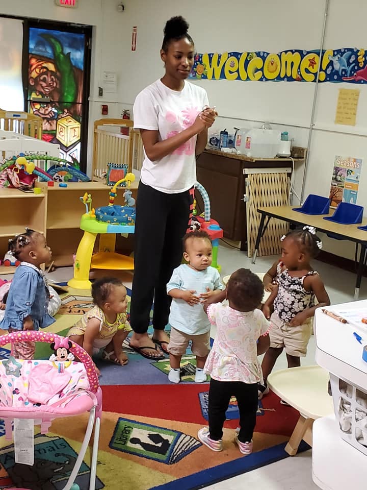 Adult person standing with several children in a classroom