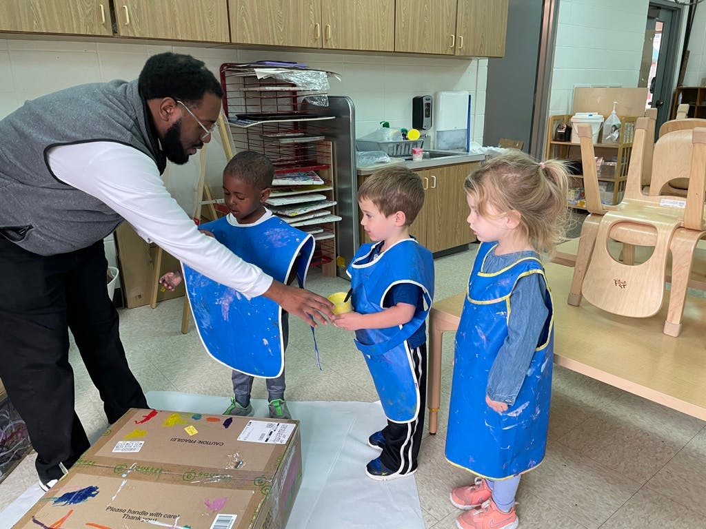 Adult helping children in blue smocks with an activity