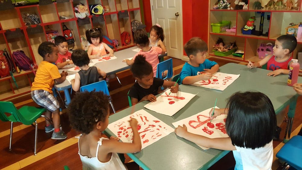 Children sitting at tables and drawing on paper in a classroom