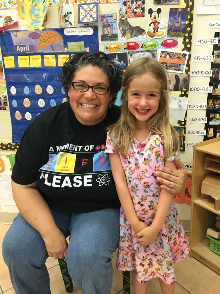 Adult and child posing together in a classroom
