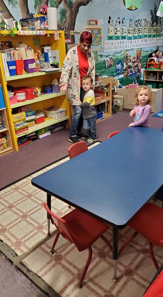 Person with two children in a classroom
