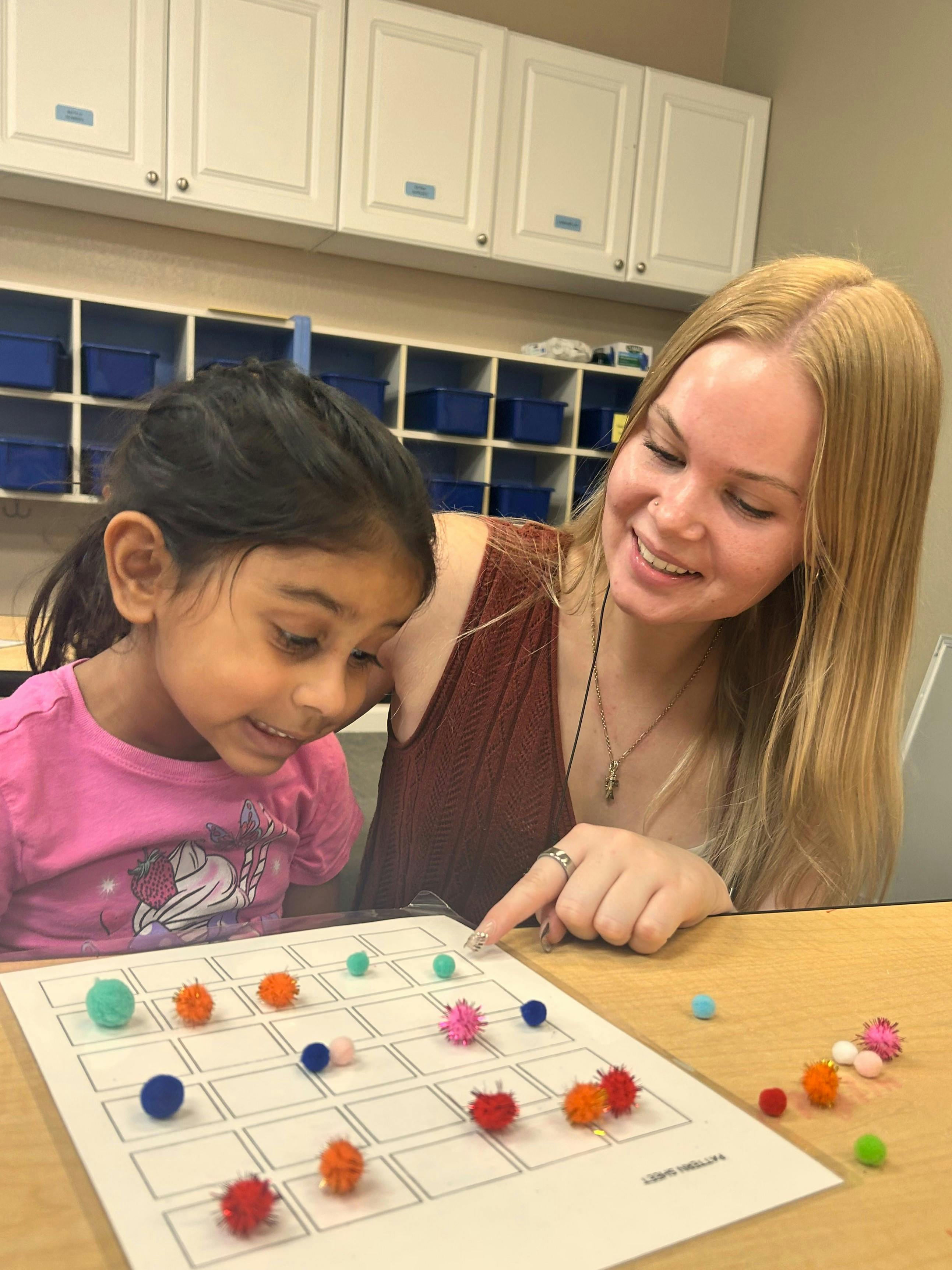 A person and a child working together on a craft activity with small pompoms