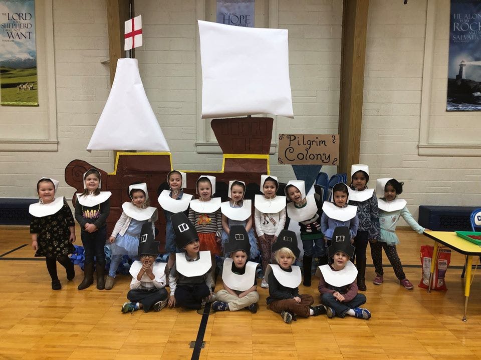 Children in costumes posing in front of a ship prop