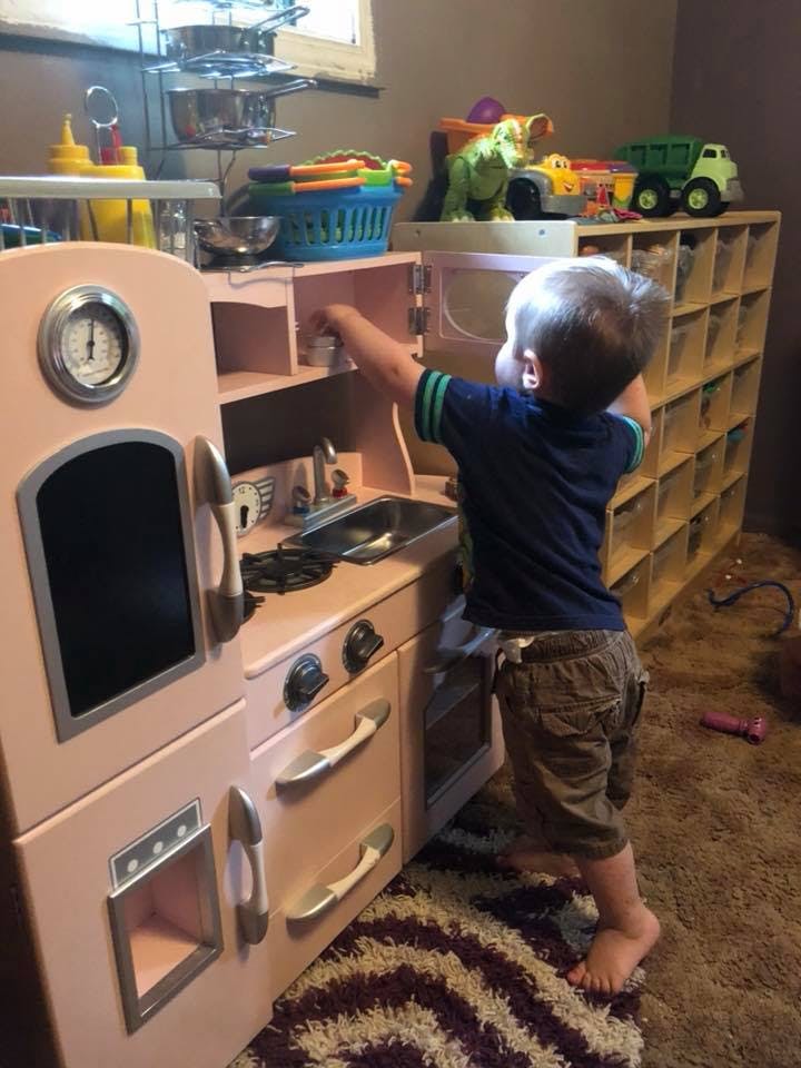 Child playing with a toy kitchen set