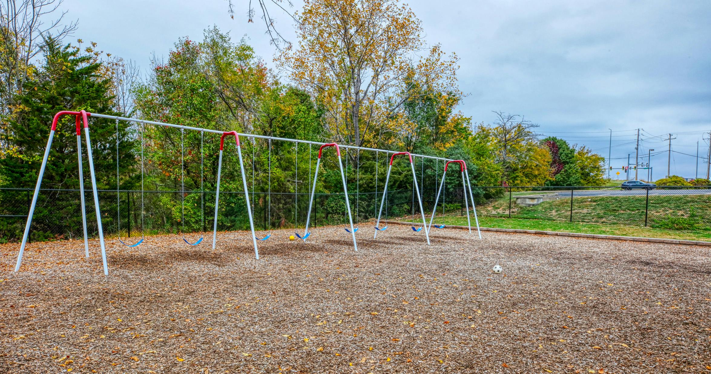 Swing set with multiple blue swings on a wood chip ground