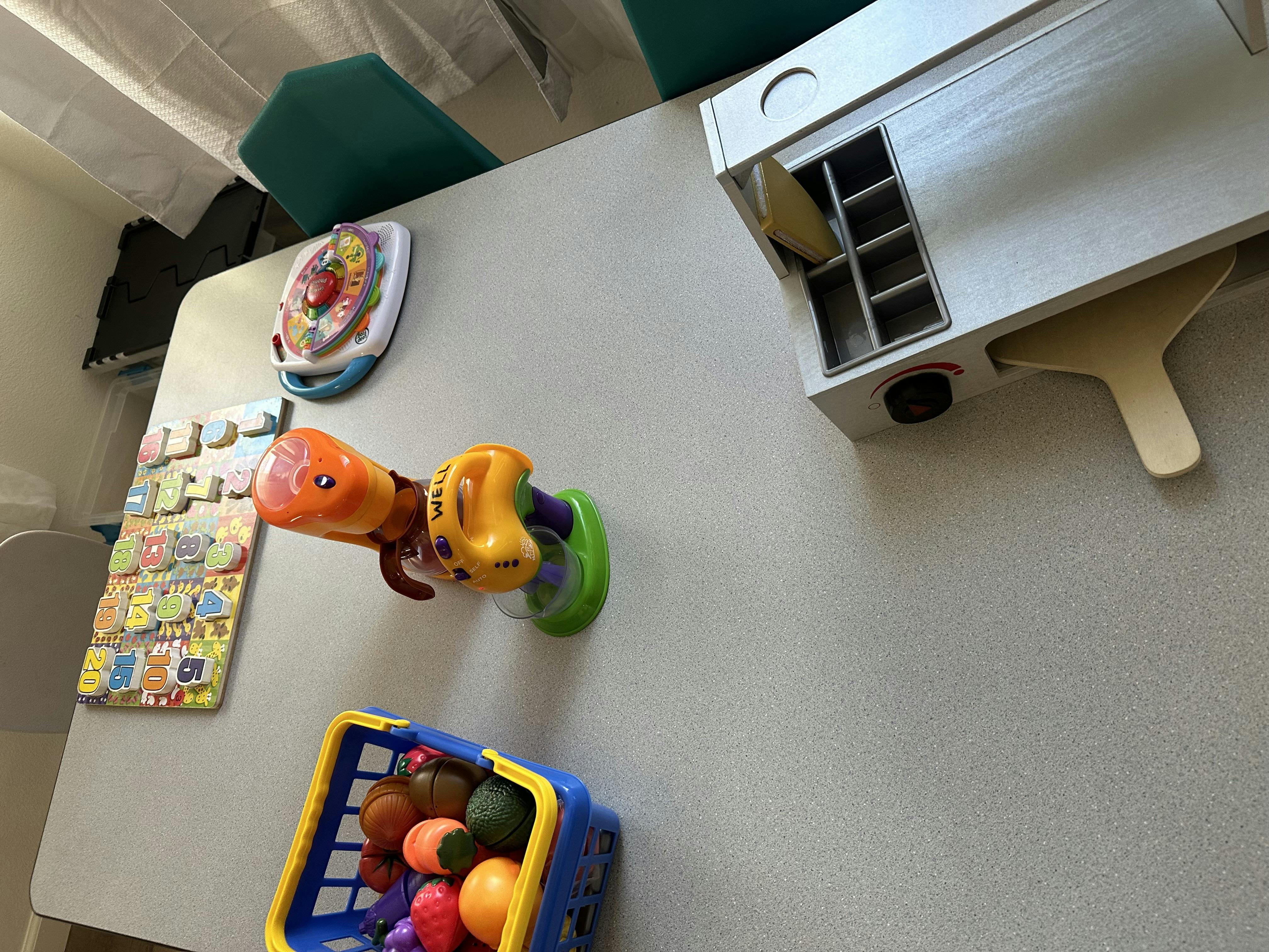 Table with various children's toys including a shopping basket with fruit