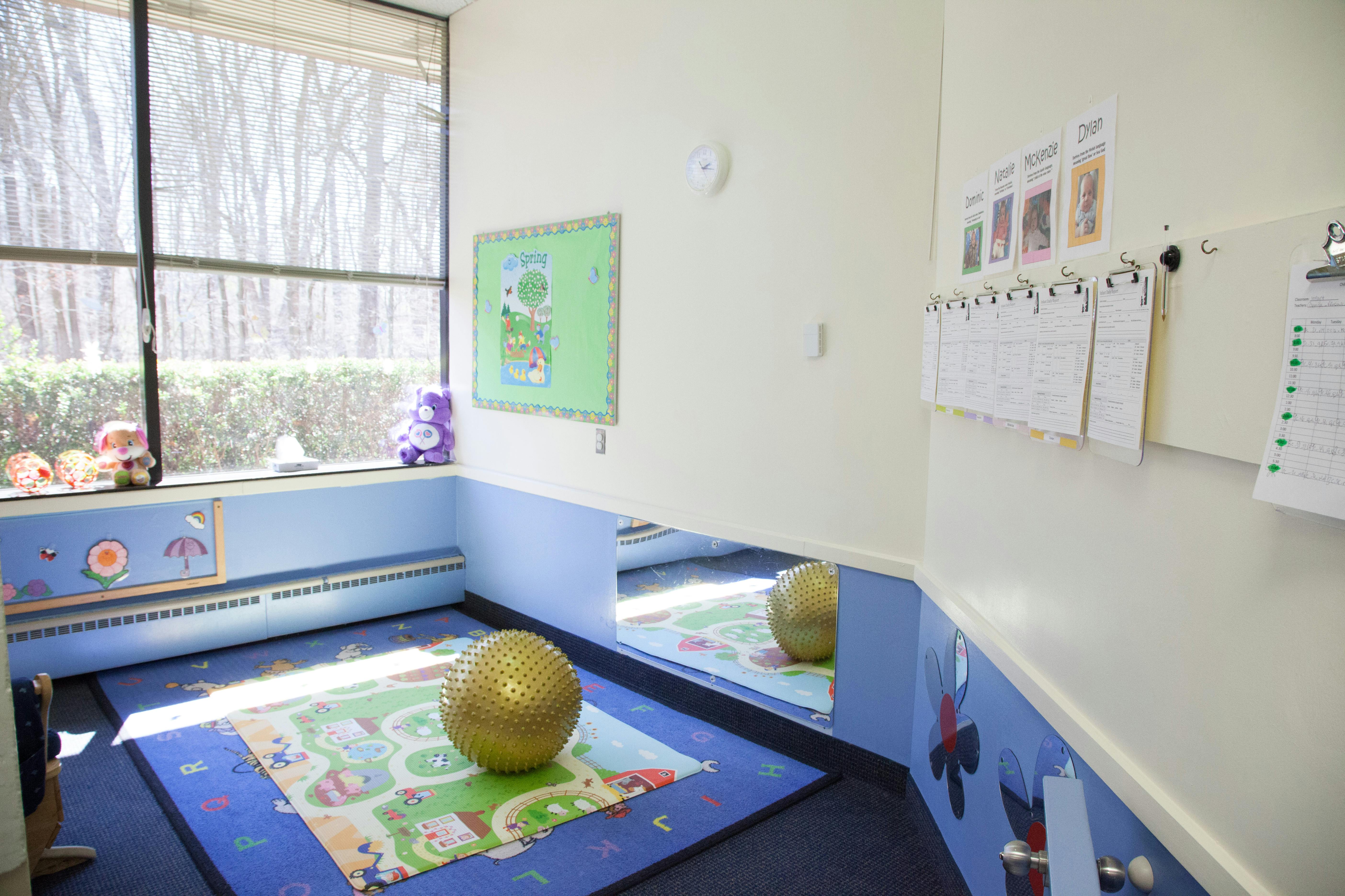 Playroom with a large window, blue walls, and a yellow exercise ball on a rug
