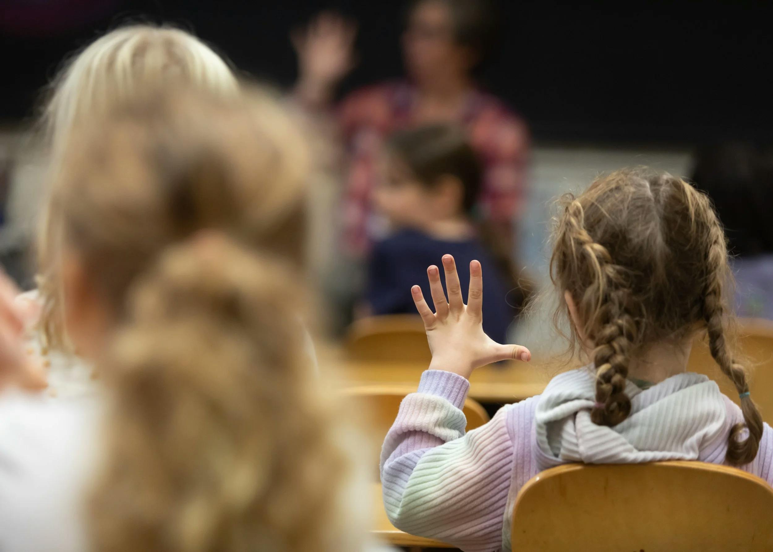 Child raising hand in a classroom