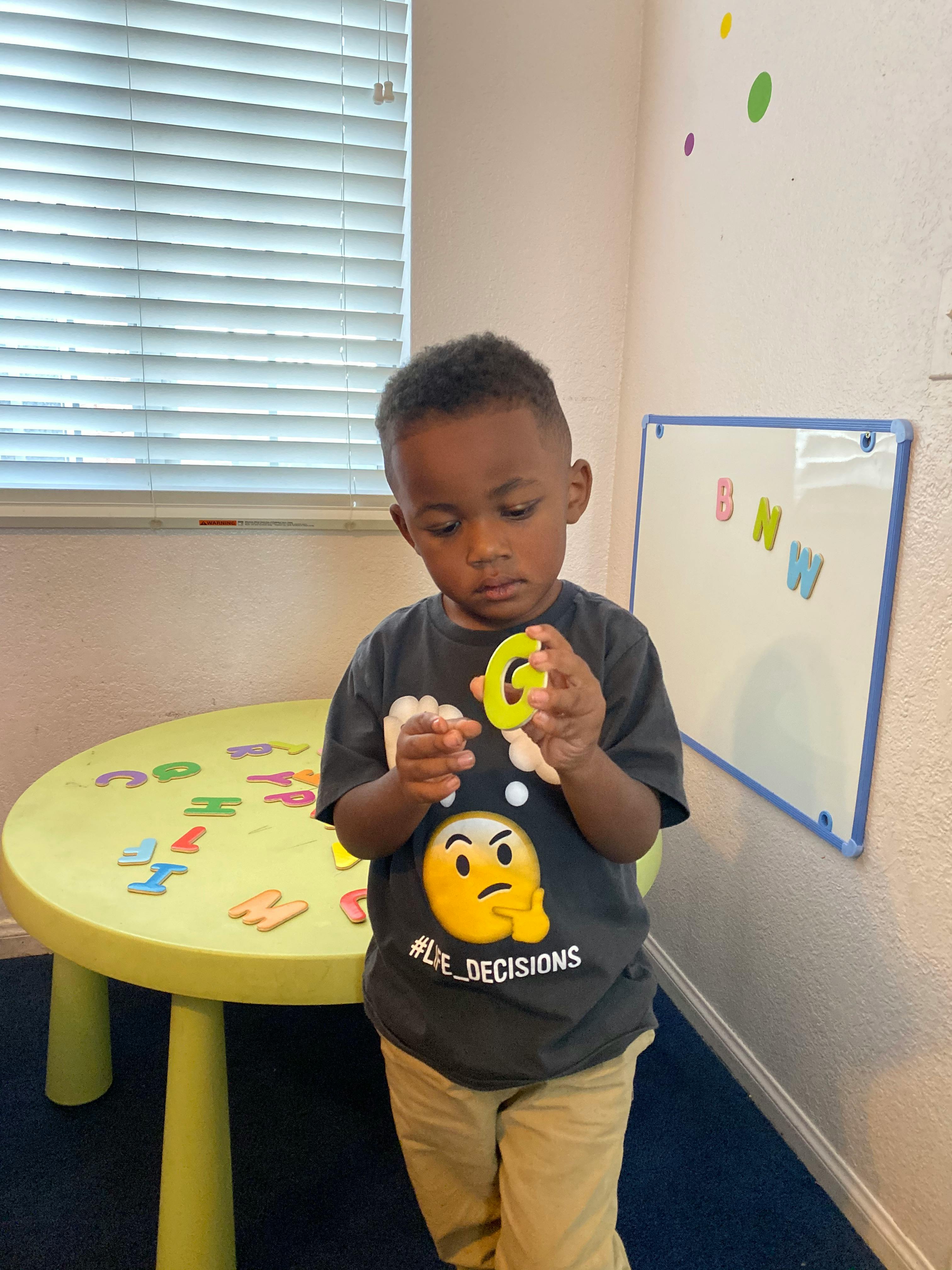 Child playing with letter magnets at a table