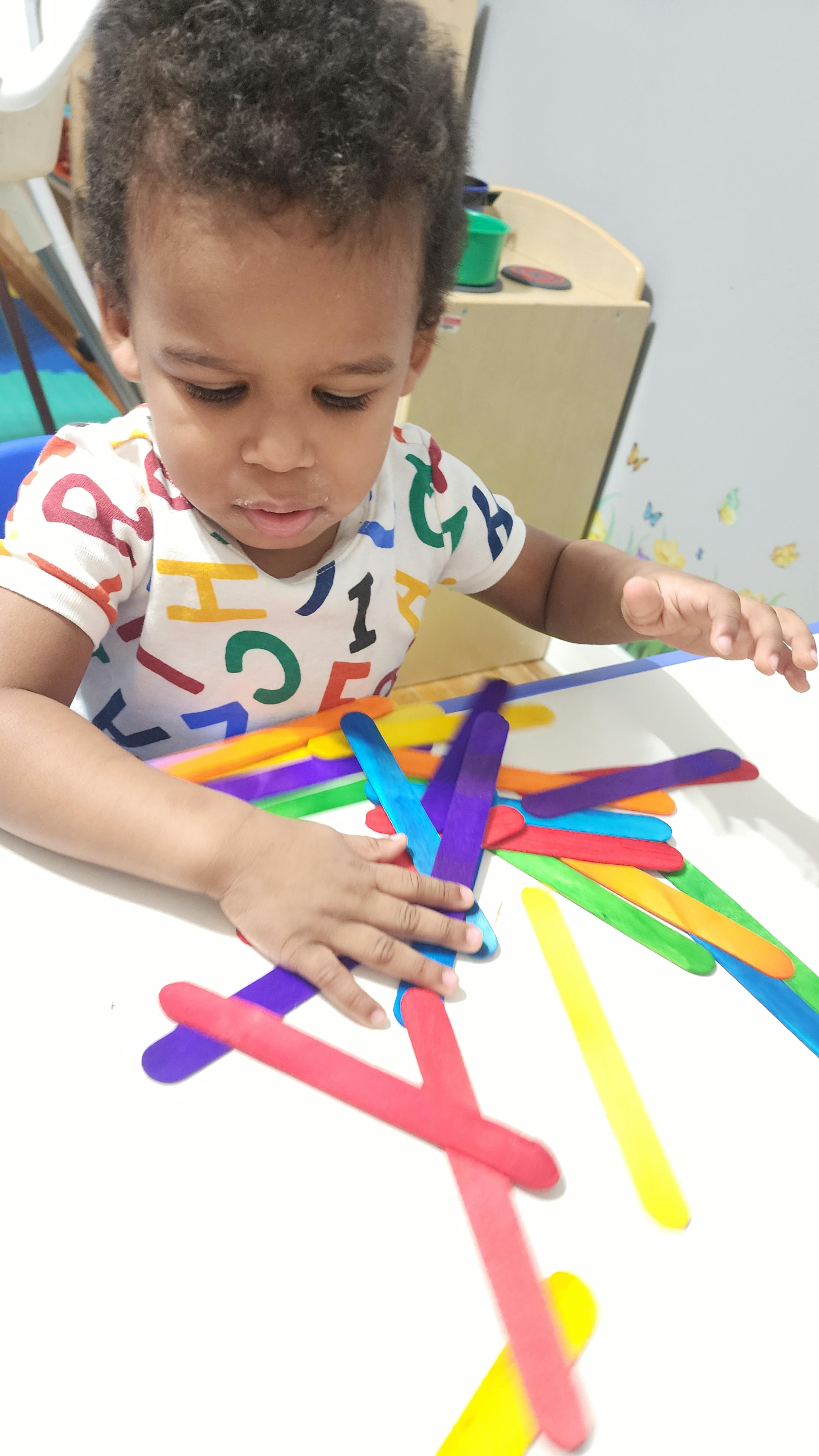 Child playing with colorful craft sticks on a table