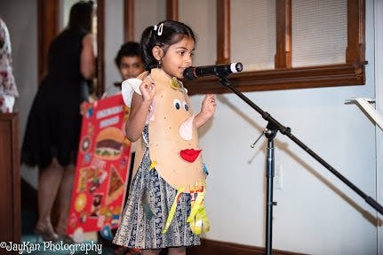 Child in costume speaking into a microphone
